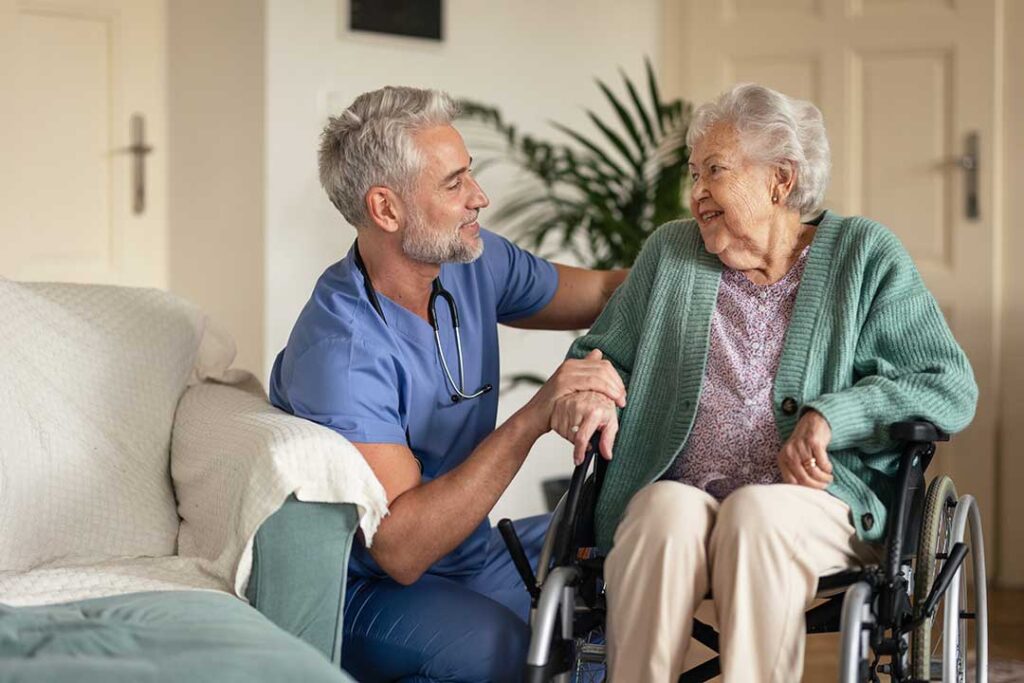 Staff member sanitizing hands beside a resident in a clean assisted living common room.