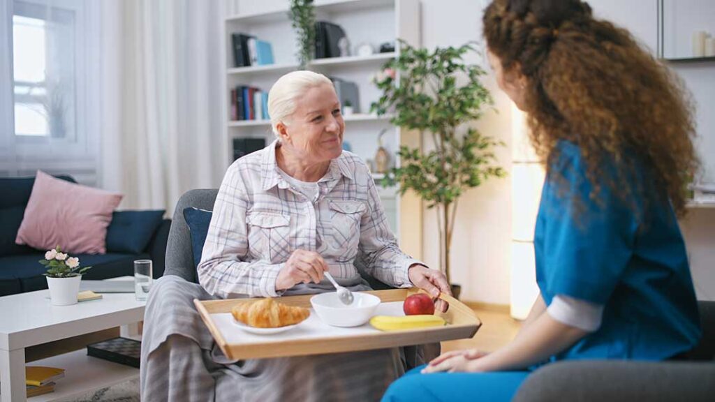 Older adult and family member reviewing a care assessment with a nurse at a kitchen table.