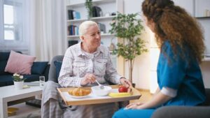 Older adult and family member reviewing a care assessment with a nurse at a kitchen table.
