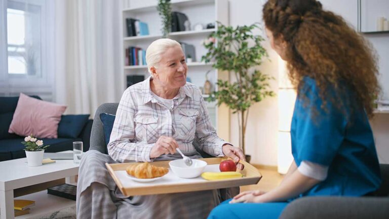 Older adult and family member reviewing a care assessment with a nurse at a kitchen table.